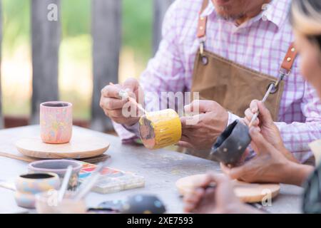 Dans l'atelier de poterie, un couple de retraités asiatiques est engagé dans des activités de fabrication de poterie et de peinture d'argile. Banque D'Images
