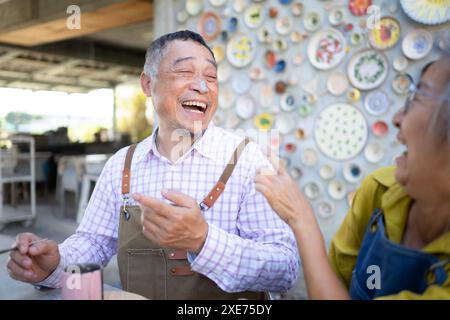 Dans l'atelier de poterie, un couple de retraités asiatiques est engagé dans des activités de fabrication de poterie et de peinture d'argile. Banque D'Images