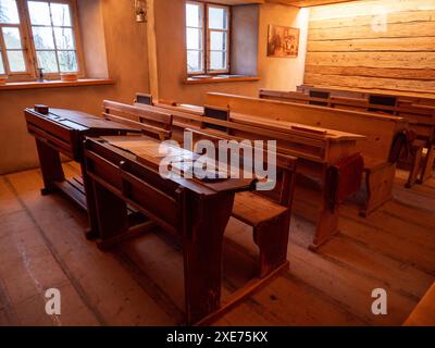 Une salle de classe vintage avec des bureaux et des bancs en bois, évoquant une atmosphère nostalgique. Banque D'Images