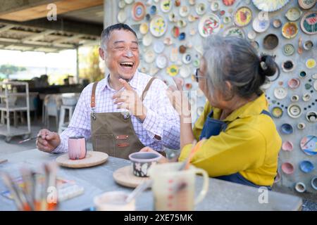 Dans l'atelier de poterie, un couple de retraités asiatiques est engagé dans des activités de fabrication de poterie et de peinture d'argile. Banque D'Images