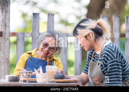 Dans l'atelier de poterie, un couple de retraités asiatiques est engagé dans des activités de fabrication de poterie et de peinture d'argile. Banque D'Images