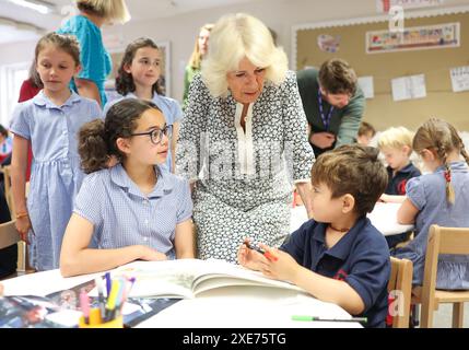 La reine Camilla rend visite à une classe d'accueil et entend parler de l'initiative de lecture 'Shepherd and Sheep', qui attribue les nouveaux élèves de la réception à un élève de 6e année, qui agit comme une amie et un modèle tout au long des nouveaux élèves de première année à l'école, lors de sa visite à Christ Church C of E Primary School à Londres. Date de la photo : mercredi 26 juin 2024. Banque D'Images