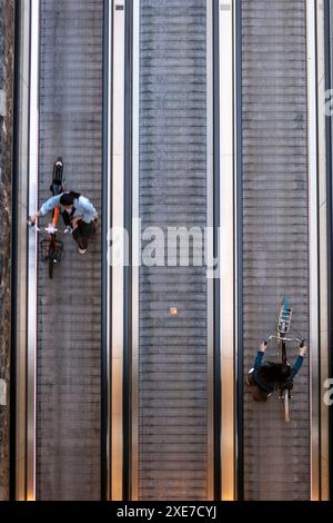 Deux femmes poussant leurs vélos sur un voyageur quittant le parking souterrain pour vélos en face de la gare ferroviaire Amsterdam Centraal aux pays-Bas. Vue de dessus. Banque D'Images