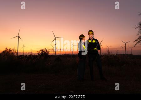 Les ingénieurs travaillant sur les éoliennes ferment au coucher du soleil, les éoliennes sont une source d'énergie alternative. Banque D'Images