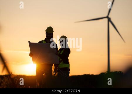 Silhouette d'ingénieur en charge de l'énergie éolienne sur fond d'éoliennes. Banque D'Images