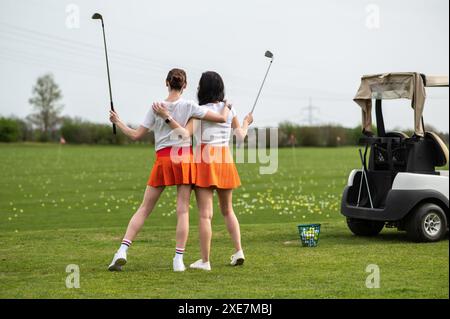 Belles filles golfeuses debout près de son transport sur le champ vert Banque D'Images