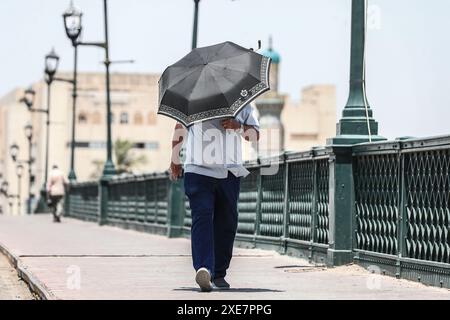 26 juin 2024, Irak, Bagdad : un homme irakien se protège du soleil sous un parapluie, au milieu d'une canicule en cours en Irak. L'Irak connaît une vague de chaleur avec des températures qui montent à plus de 45 degrés Celsius. Photo : Ameer Al-Mohammedawi/dpa Banque D'Images