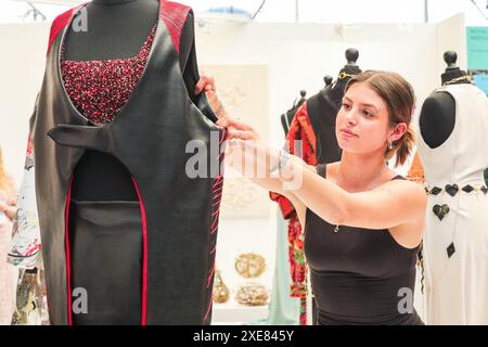 Londres, Royaume-Uni. 26 juin 2024. Maddie Smith de la Royal School of Needlework apporte la touche finale à son présentoir design. Les diplômés montrent leurs créations au New designers Design Graduate Show au Business Design Centre. L'événement se déroule sur deux semaines, mettant en lumière de nouveaux talents dans la mode, textiles, meubles, design de produits, illustration, et bien plus encore. Crédit : Imageplotter/Alamy Live News Banque D'Images