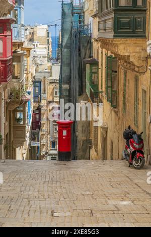 Valleta, Malte 07 septembre 2023 rouge malte boîte de pilier isolé au-dessus des marches en pierre avec moto Banque D'Images