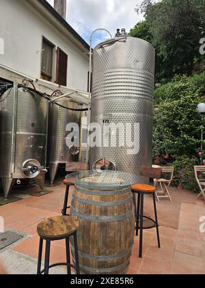 Table en tonneau de vin et tabourets de bar devant de grands tonneaux de vin en métal. Photo verticale. Banque D'Images