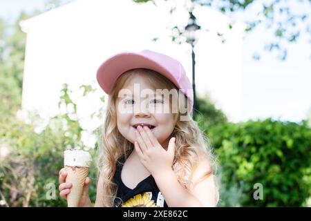 Heureuse blonde caucasienne jeune fille avec de la crème glacée. Enfant heureux dans le parc Banque D'Images