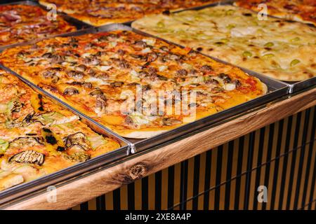 Savoureuses pizzas carrées sur plateaux métalliques Banque D'Images