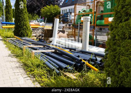 Chantier de construction avec égout en plastique et conduites d'eau de différentes couleurs empilées dessus. Banque D'Images