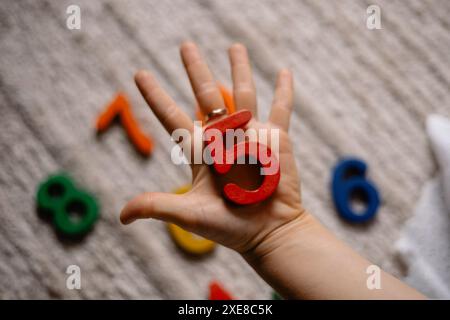 jeune femme tenant des numéros en bois multicolores dans ses mains Banque D'Images