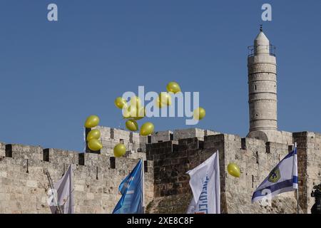 Jérusalem, Israël. 26 juin 2024. Des ballons d'hélium jaunes sont lâchés pour soutenir les otages israéliens et leurs familles alors que des dizaines d'entre eux participent au premier marathon de deux jours à la porte de Jaffa, organisé par la municipalité de Jérusalem pour encourager la forme physique et un mode de vie sain. Crédit : NIR Alon/Alamy Live News Banque D'Images