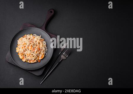 Délicieuses nouilles avec poulet et légumes ou udon sur une plaque en céramique noire Banque D'Images