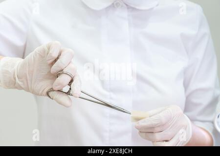 Médecin portant des gants à l'aide d'une pince chirurgicale pour ouvrir le pansement Banque D'Images