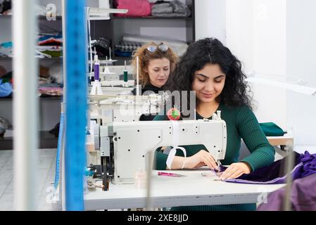 Les jeunes tailleurs cousent des vêtements sur la machine à coudre dans le studio d'atelier Banque D'Images