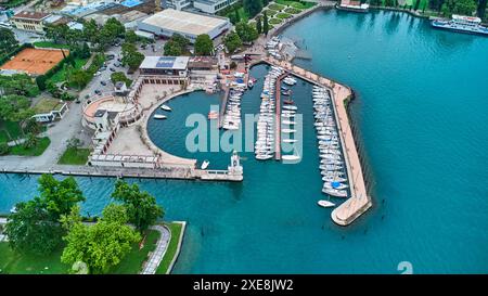 Riva del Garda, Lac Garada, Italie - 25 juin 2024 : vue plongeante sur les toits de Riva del Garada, bateaux et bateaux accostent dans une rangée sur la promenade, de la station. *** Über den Dächern von Riva del Garada aus der Vogelperspektive, Boote und Schiffe legen an der Promenade in einer Reihe an, des Urlaubsortes. Banque D'Images