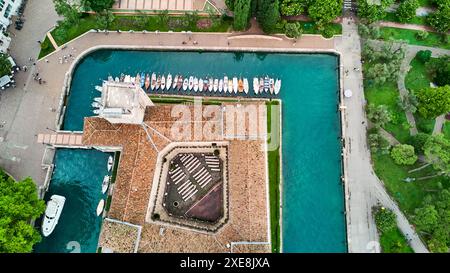 DATE D'ENREGISTREMENT NON INDIQUÉE Riva del Garda, Lac Garada, Italie - 25 juin 2024 : vue plongeante sur les toits de Riva del Garada, bateaux et bateaux accostent dans une rangée sur la promenade, de la station. *** Über den Dächern von Riva del Garada aus der Vogelperspektive, Boote und Schiffe legen an der Promenade in einer Reihe an, des Urlaubsortes. Banque D'Images