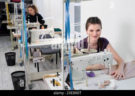 Les jeunes tailleurs cousent des vêtements sur la machine à coudre dans le magasin de tailleur Banque D'Images