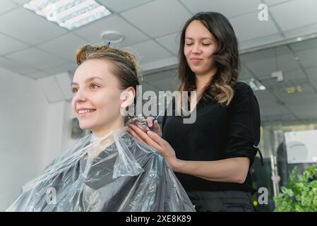 Femme ayant les cheveux déjoués tout en colorant dans un salon de coiffure Banque D'Images