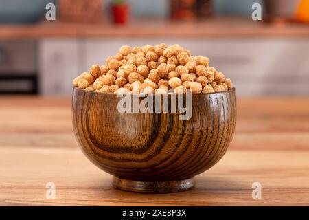 Bol de petites boules de céréales de petit déjeuner aromatisées à la cannelle grillée sur une table de cuisine en bois Banque D'Images