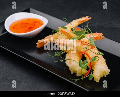 Tempura de crevettes frites avec sauce Chili douce sur assiette en pierre noire Banque D'Images