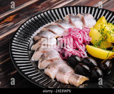 Gros plan de hareng mariné savoureux avec pommes de terre et oignons dans l'assiette Banque D'Images