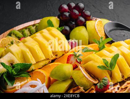 Une assiette de fruits assortis sur pierre noire Banque D'Images