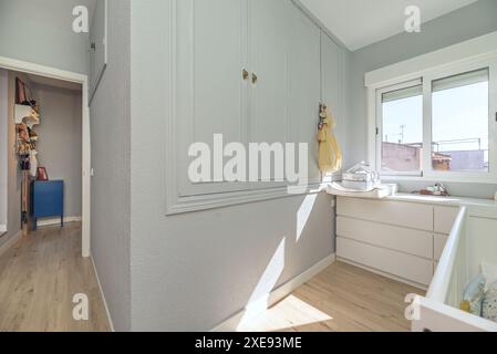 Chambre avec mobilier blanc, radiateurs, murs peints en vert clair, armoires encastrées et lit bébé Banque D'Images