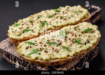 Pain grillé avec pâte d'avocat, œufs, fromage à la crème, sel, épices et herbes Banque D'Images