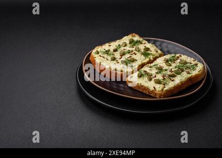 Pain grillé avec pâte d'avocat, œufs, fromage à la crème, sel, épices et herbes Banque D'Images