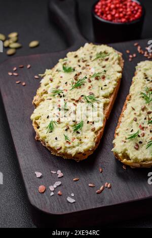 Pain grillé avec pâte d'avocat, œufs, fromage à la crème, sel, épices et herbes Banque D'Images