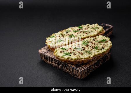 Pain grillé avec pâte d'avocat, œufs, fromage à la crème, sel, épices et herbes Banque D'Images