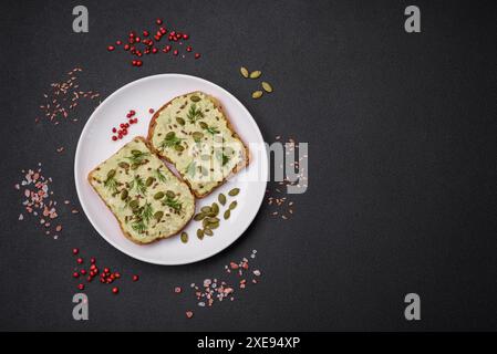 Pain grillé avec pâte d'avocat, œufs, fromage à la crème, sel, épices et herbes Banque D'Images