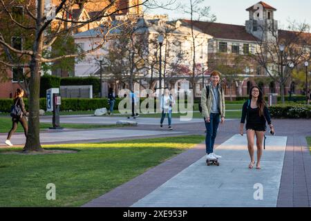 Los Angeles, Californie États-Unis - 28 mars 2017 : skateboarder et fille traversent USC Walkway. Banque D'Images