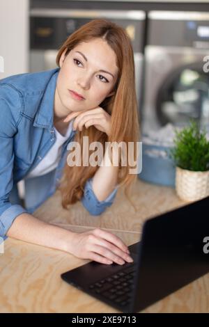 jeune travailleuse assise sur le lieu de travail chez les nettoyeurs à sec Banque D'Images