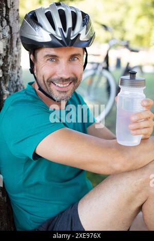 joyeux cycliste souriant homme de boire de l'eau pendant que vous vous reposez Banque D'Images