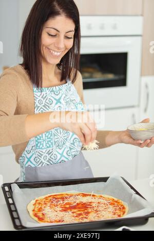 belle femme portant un tablier préparant une pizza Banque D'Images