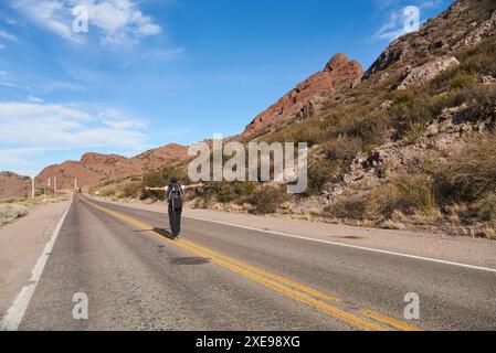 Femme randonneur ouvrant les bras au milieu de la route, insouciante, heureuse, vivant une aventure pendant ses vacances dans les montagnes de Potrerillos, hommes Banque D'Images