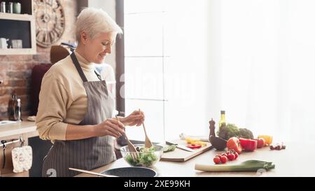 Femme faisant la salade dans la cuisine moderne avec lumière naturelle Banque D'Images