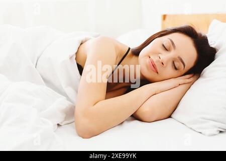 Femme couchée dans le lit avec les yeux fermés, dormant paisiblement Banque D'Images