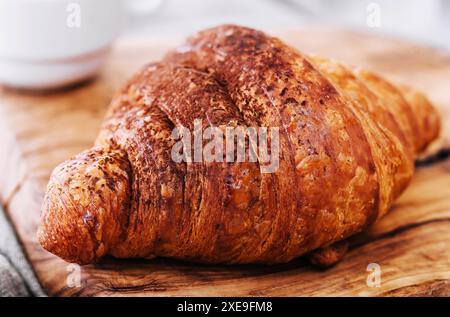 Croissant avec de la poudre de chocolat sur une planche de bois Banque D'Images