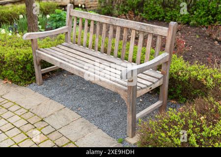 Un banc de parc en bois vide se dresse sur un sol pavé un jour d'été Banque D'Images