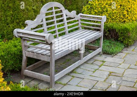 Un banc de parc vintage vide se dresse sur un sol pavé un jour d'été Banque D'Images