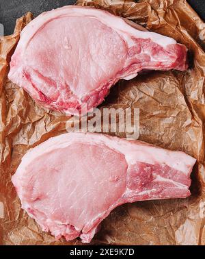 Plusieurs steaks de porc crus sur du papier cuisson Banque D'Images