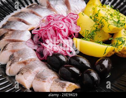 Gros plan de hareng mariné savoureux avec pommes de terre et oignons dans l'assiette Banque D'Images