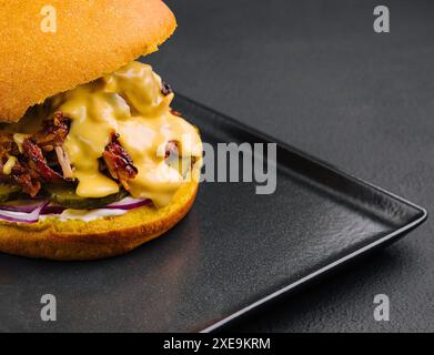 Délicieux burger avec de la viande déchirée sur un plateau noir Banque D'Images