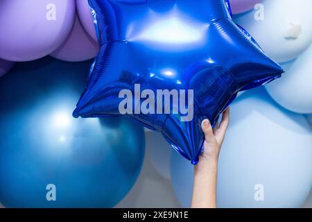 GOIANIA GOIAS BRÉSIL – JUIN 25 2024 : détail d'une main d'enfant attrapant un ballon bleu en forme d'étoile. Banque D'Images